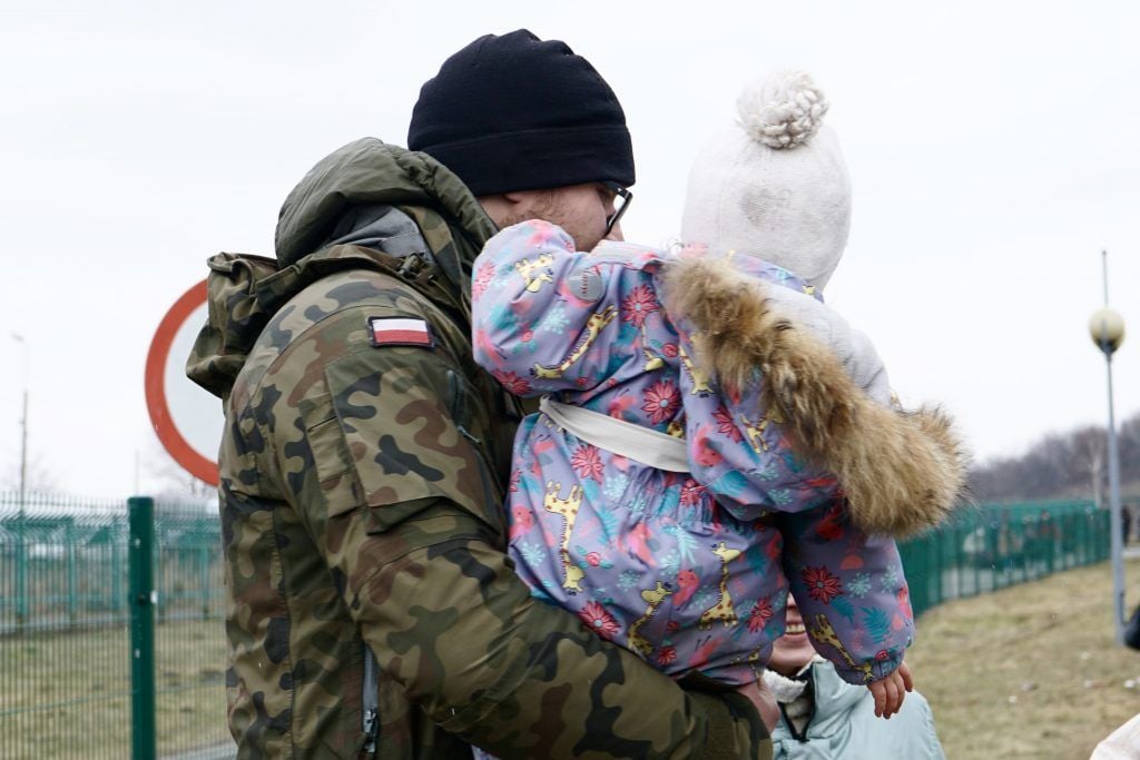Oficial fronterizo polaco carga a una niña ucraniana que acaba de pasar la frontera. Medyka, 9 de marzo de 2022. / Foto: Alejandro Taquechel