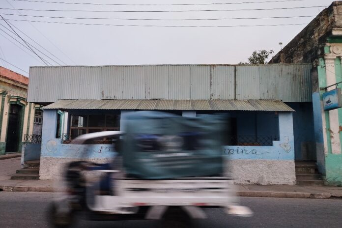 Al fondo, antiguo establecimiento gastronómico desmantelado. En primer plano, un triciclo eléctrico. Matanzas, septiembre de 2026