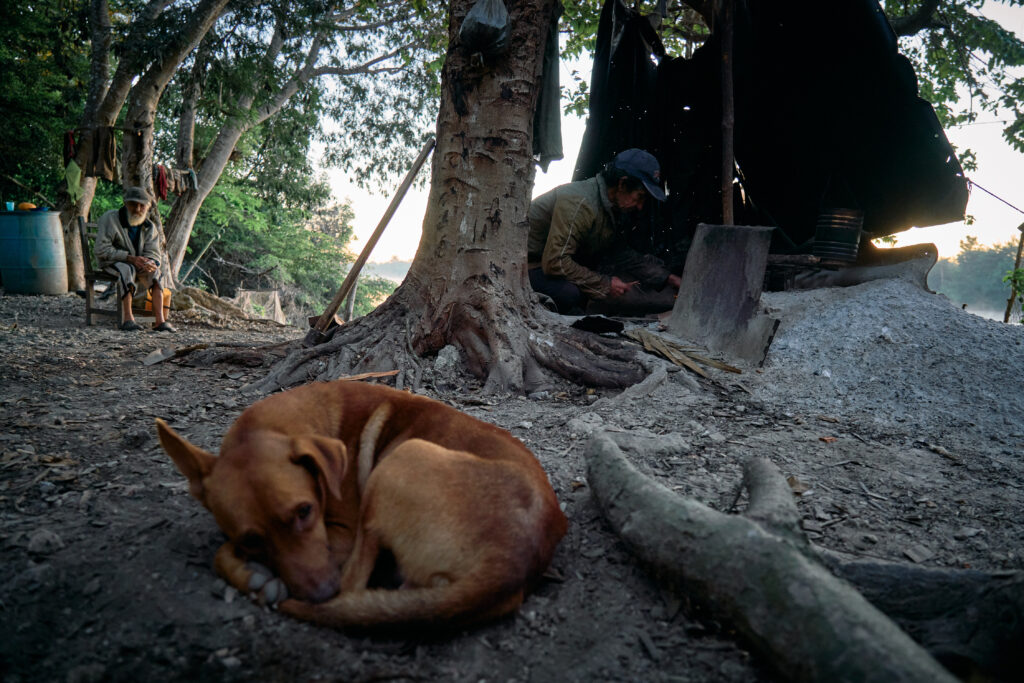 Eulogio cocina mientras su perro duerme. Al fondo, Enrique.