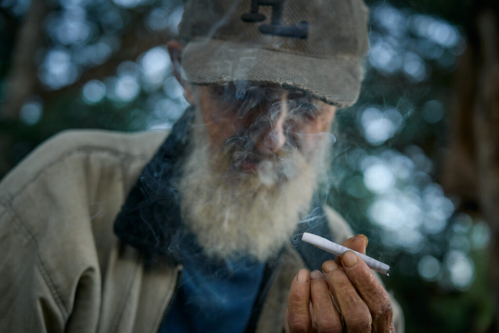 Enrique fuma un cigarro recién armado con restos de tabaco y papel