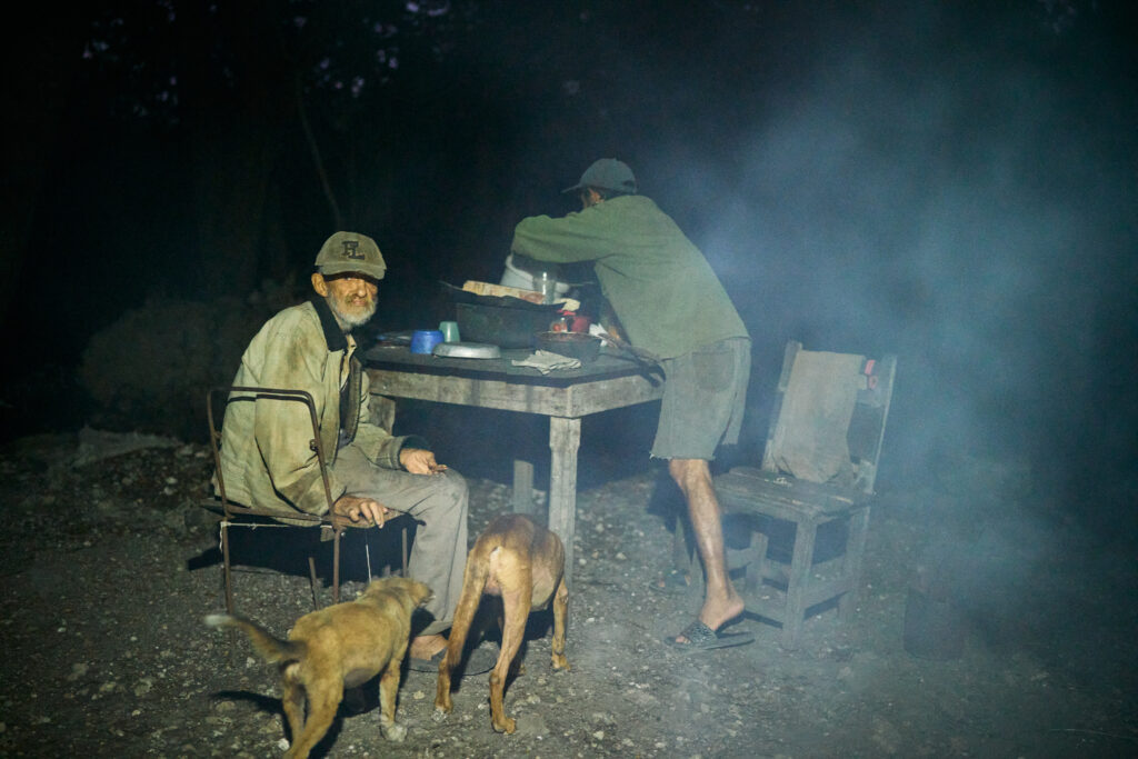 Ambos hermanos se sientan a comer mientras los perros los acompañan.